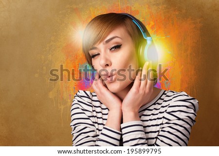 Pretty young woman with headphones listening to music in front of a painted wall