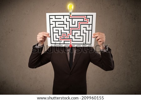 Young businessman holding a paper with a labyrinth on it in front of his head