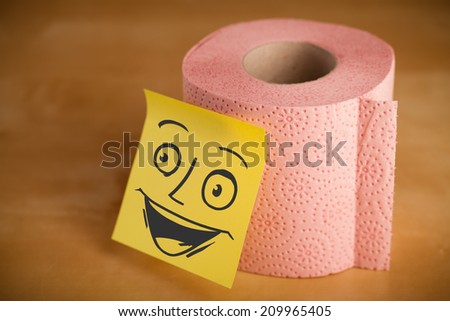 Drawn smiley face on a post-it note sticked on a toilet paper roll