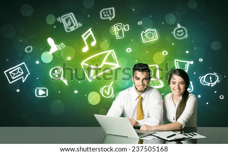 Business couple sitting at the black table with social media symbols on the background