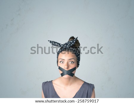 Young woman with taped mouth. Isolated on gray background
