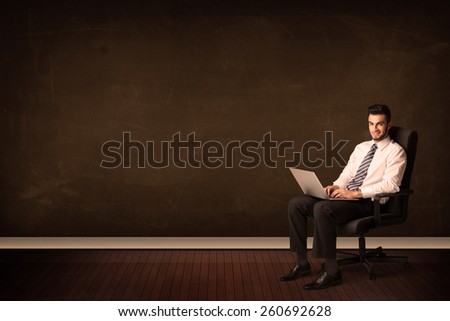 Businessman holding high tech laptop on brown background with copyspace