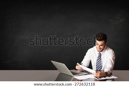 Business man sitting at black table with a laptop on black background
