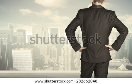 Businessman from the back in front of a city view on the window