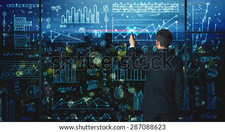 Businessman drawing business statistics on glass wall