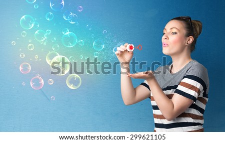 Pretty lady blowing big colorful bubbles on blue background
