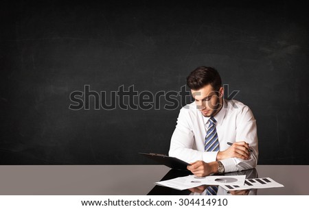 Business man sitting at black table on black background
