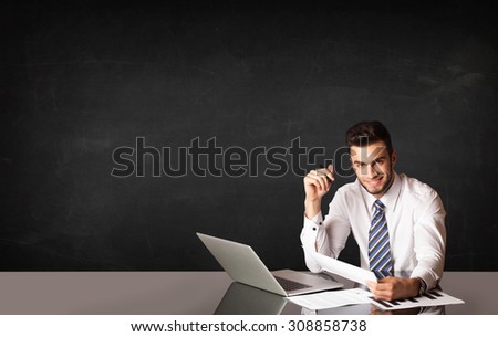Business man sitting at black table with a laptop on black background