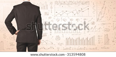 Businessman from the back in front of diagrams and graphs background
