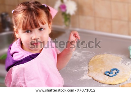 Happy little girl cooks biscuits in the kitchen