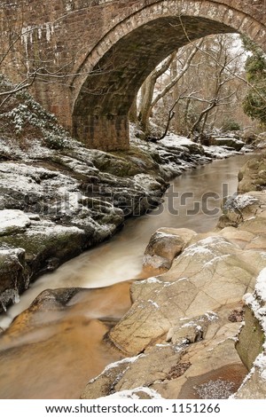 Snowy stream under arched bridge