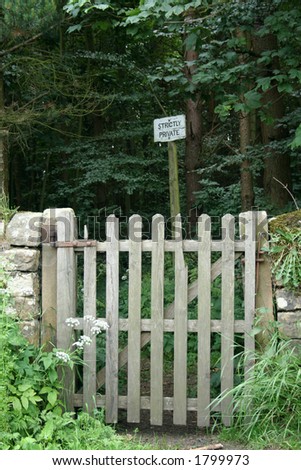 Old broken wooden gate leads to a path thorough the wood but the sign \