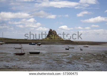 Boats are on the sand at Low tide with Lindisfarne Castle in the backgroung