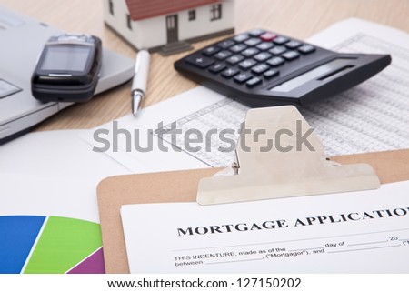 mortgage application form with laptop, phone; calculator and house