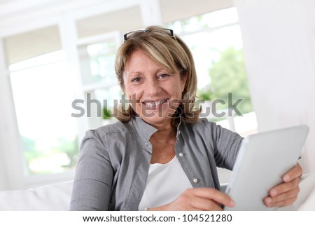 Smiling senior woman at home connected on internet