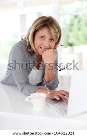 Senior woman in front of laptop with cup of coffee