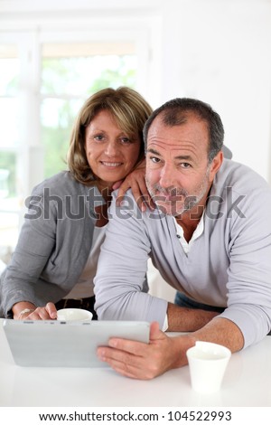 Senior couple drinking coffee in front of tablet