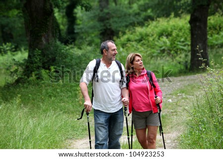Retired elderly people hiking in forest pathway
