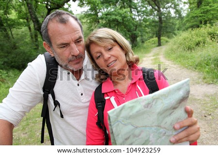Senior couple rambling in forest with map