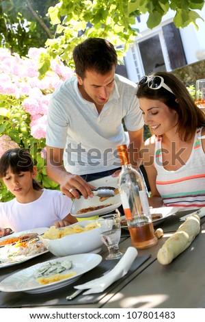 Father serving grilled meat to family