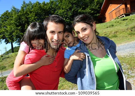 Parents and children standing in front of mountain log cabin