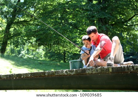 Father fishing with son on a bridge in the mountain