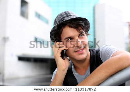 Trendy guy with hat talking on mobile phone