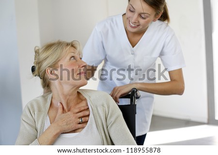 Nurse at home with elderly person in wheelchair