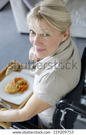 Senior woman in wheelchair holding lunch tray