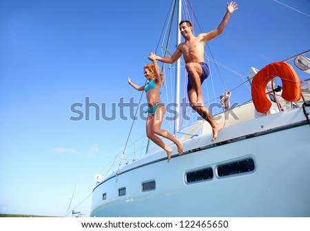 Young couple jumping in water from yacht