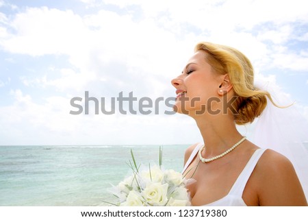 Portrait of beautiful bride with eyes shut by the beach