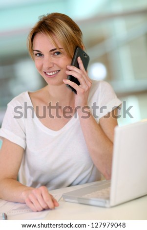 Cheerful woman at work talking on cellphone