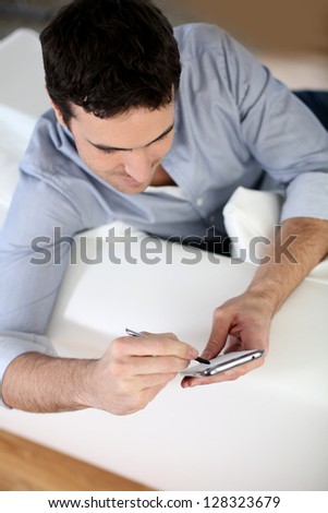 Upper view of man in sofa using smartphone
