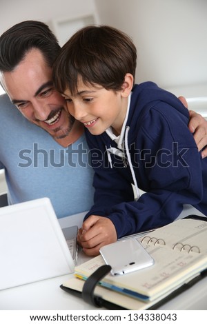Man showing to young boy how to use laptop