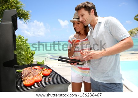 Cheerful couple in holidays preparing grilled meat