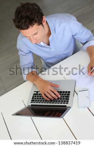 Upper view of smart guy working on laptop at home