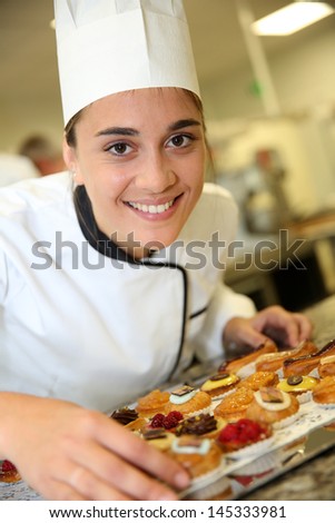 Cheerful pastry cook holding tray of pastries