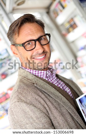 Smiling man buying newspaper in book stand