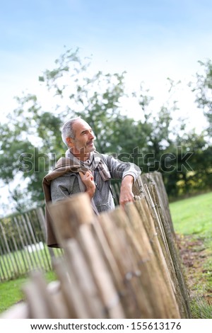Mature man standing by fence in countryside