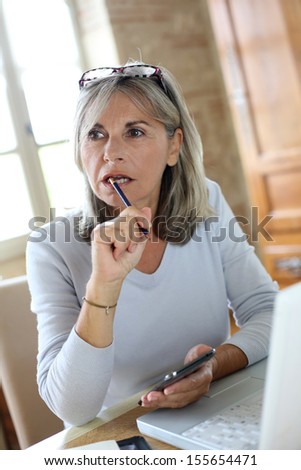 Senior woman at home figuring out income tax