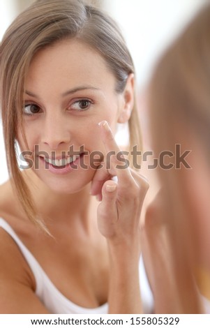 Young woman applying  anti-wrinkles cream