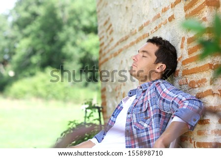 Man relaxing on bench during week-end in countryside