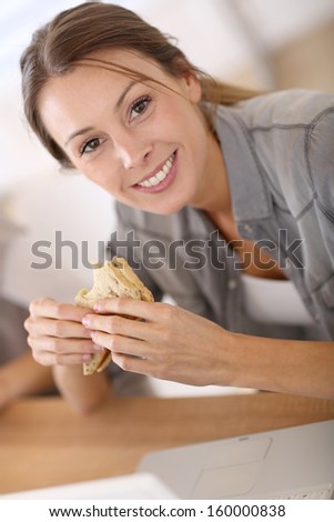 Business girl eating sandwich in front of laptop