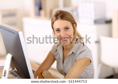 Beautiful blond girl working in office on desktop