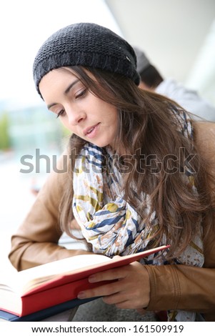 Student girl reading book outside school building