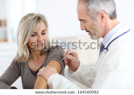 Doctor injecting vaccine to senior woman