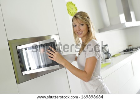 Woman at home using microwave oven