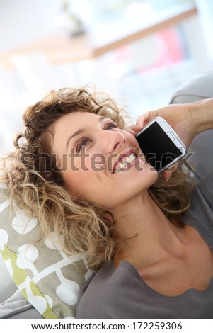 Woman talking on smartphone laid in sofa