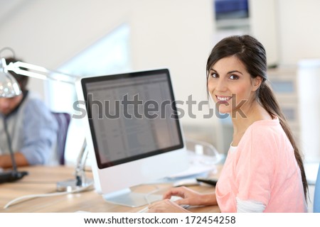 Beautiful girl sitting in office in front of desktop