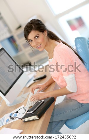 Beautiful girl sitting in office in front of desktop